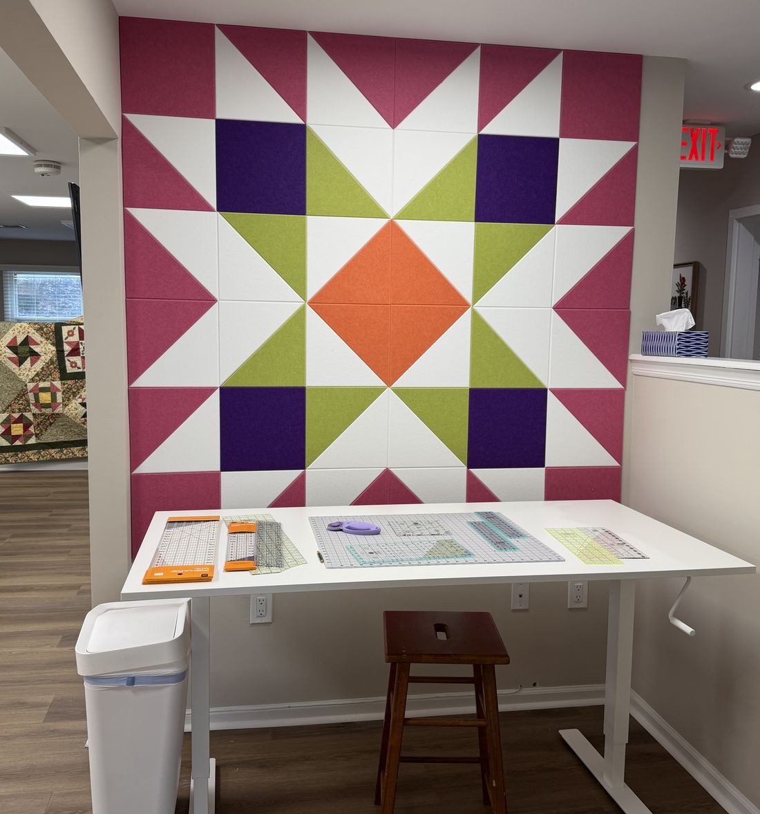 The studio's felt quilt-block accent wall in magenta, purple, lime, and orange, with a cutting table